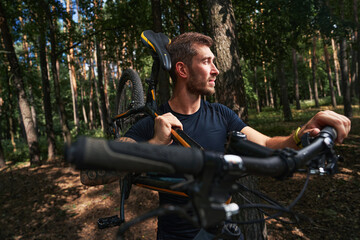Calm athletic man with bike in nature