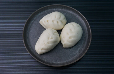 steamed fresh vegetables bun white baozi in leaf shape on dark grey wood background dim sum halal menu