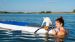 Dog jack russell terrier swims on the board with the owner. A woman and her pet spend time together at the lake