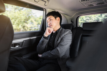 Wall Mural - business man thinking while sitting in the back seat of car