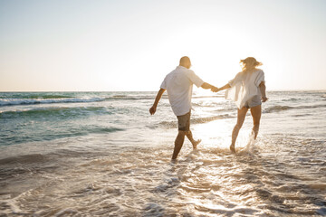 Wall Mural - Young beautiful couple walking on beach near sea