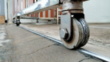Close Up Sliding Door Wheels. Metal Scroll Wheel On Steel Track On Cement Floor Background. Selective Focus