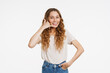 Young ginger woman in t-shirt smiling and making handset gesture
