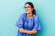 Young caucasian nurse isolated on blue background laughing and having fun.