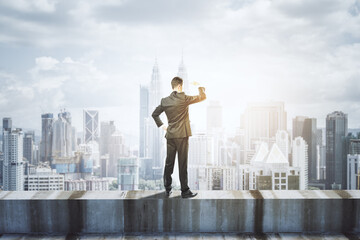 Wall Mural - back view of young business man standing on concrete edge of building on city background with mock u