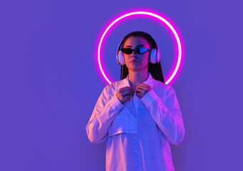 Young woman's portrait isolated on blue studio background in multicolored neon light with geometric luminescent shape cirlce