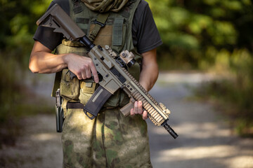 Close up of a man standing with an airsoft assault rifle in military uniform