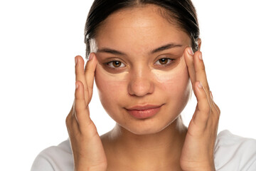 Wall Mural - Head shot of a young beautiful woman applies concealer under her eyes