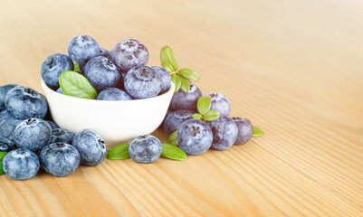 Wall Mural - fresh blueberries in a plate on a wooden table, front view