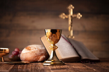 Wall Mural - Catholic religion concept. Catholic symbols composition. The Cross, Holy Bible, rosary and golden chalice on the altar.