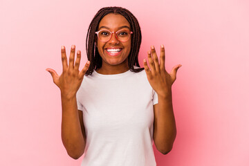 Young african american woman isolated on pink background  showing number ten with hands.