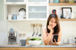 © interstid - Smiling beautiful asian woman using smartphone mobile in the kitchen