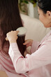 © DragonImages - Close-up image of woman letting friend or sister to brush her long tangles hair