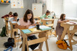 © pressmaster - Group of clever intercultural schoolchildren working individually while sitting by desks