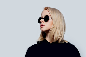 Wall Mural - blonde in black and round sunglasses on a white background