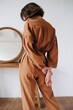 Back image of sexy woman in a brown jumpsuit holding hands behind her back