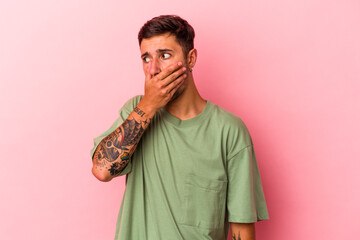Young caucasian man with tattoos isolated on yellow background  thoughtful looking to a copy space covering mouth with hand.