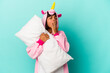 © Asier - Young mixed race woman wearing a unicorn pajama holding a pillow isolated on blue background