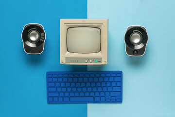 Wall Mural - A monitor, a keyboard and two computer speakers on a two-tone blue background. Flat lay.