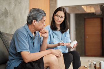 Wall Mural - Female doctor helping Asian male patient to take medicine checking the health in-home medical service for visiting sick older people after retirement, residential caregiver from professional.