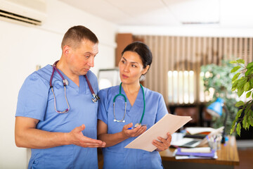 Wall Mural - Two professional doctors checking the patient papers in a doctor office in clinic