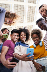 Vertical photo. Low angle view of a group of young teenagers holding cell phones. Concept of technology, connection.