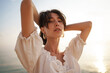 © fotofabrika - Portrait of young brunette haired woman at the beach at sunset