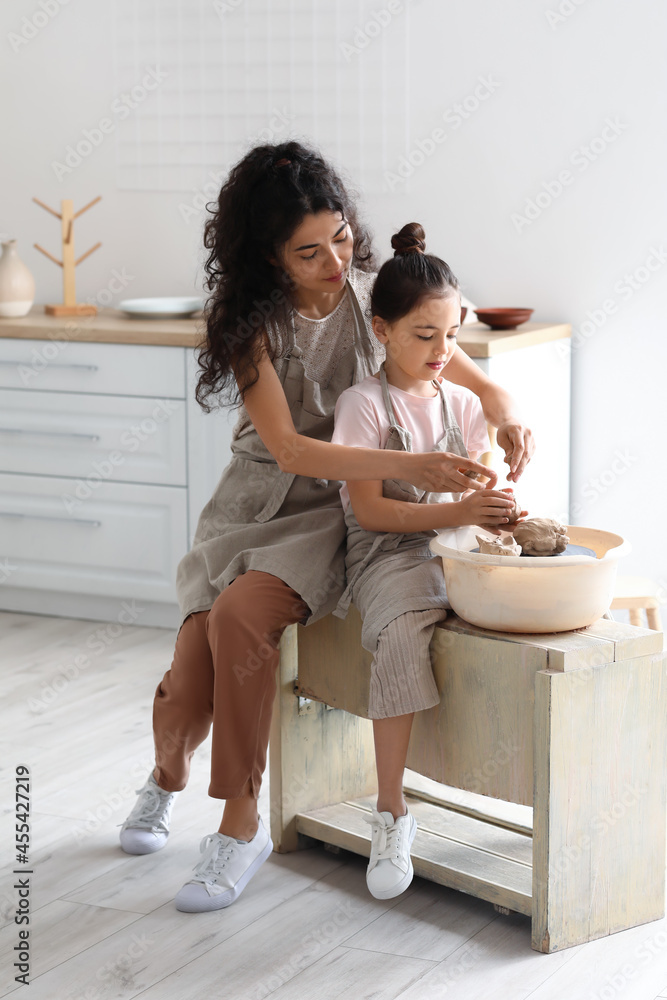 Little girl with her mother making ceramic pot at home