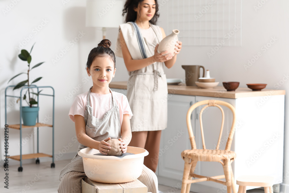 Little girl with her mother making ceramic pot at home