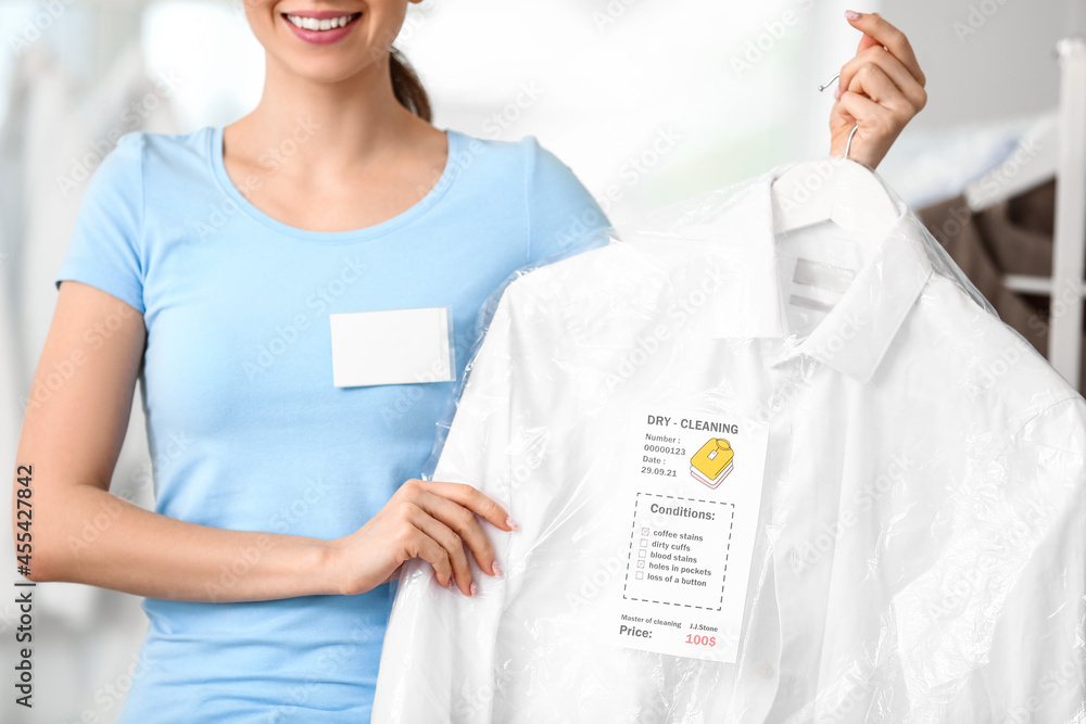 Female worker with clothes at modern dry-cleaner's