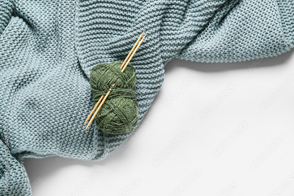 Yarn with knitting needles and plaid on white background