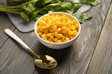 Wall Mural - Bowl with corn kernels on wooden background, closeup