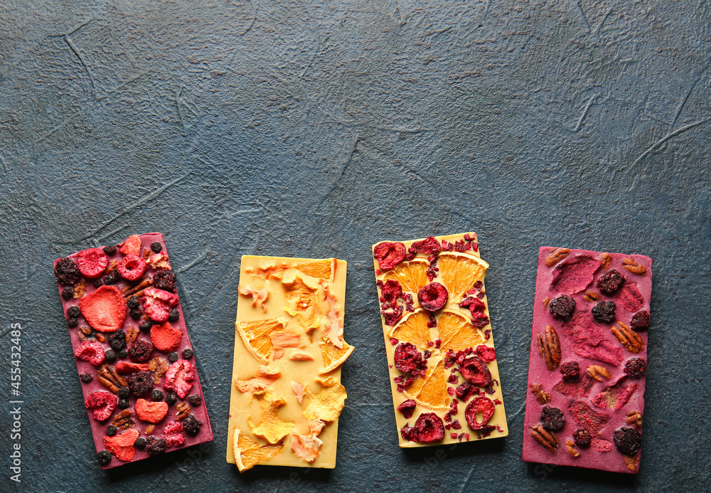 Handmade chocolate bars with fruits, berries and nuts on dark background