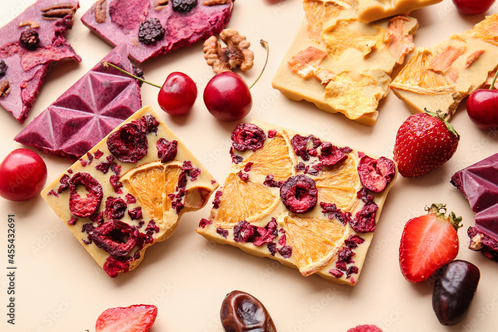 Handmade chocolate bars with fruits and berries on color background