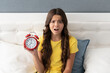 Worried girl child hold alarm clock being upset with oversleeping morning, late