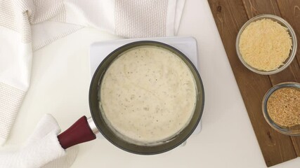 Wall Mural - Alfredo sauce in a saucepan close up. Asparagus casserole in a creamy Alfredo sauce topped with bread crumbs and Parmesan cheese step by step recipe. 