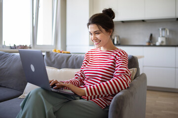 smiling girl freelancer using laptop studying online working from home office. happy millennial woma