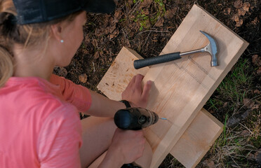 Poster - Caucasian woman working with a drill, building outdoors