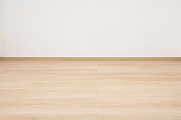 Empty wooden floor with white concrete wall.