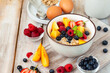 Bowl with vegan granola with fresh ripe organic berries, peach, plant milk, mint. Concept of dieting, detox, tasty simple super food, healthy low calories breakfast. Wooden background, close up
