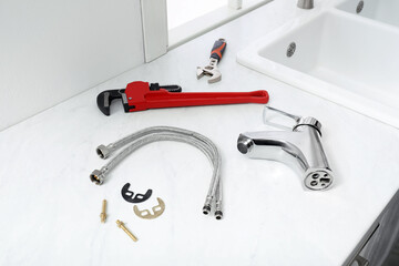 Poster - Parts of water tap and wrenches on white marble countertop in kitchen