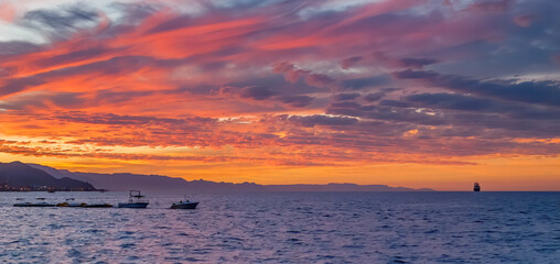 Wall Mural - Colorful clouds during sunrise above sea and mountains