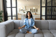 © Prostock-studio - Stress management. Peaceful young lady in casual wear meditating with closed eyes on couch at home
