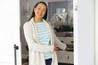 © wavebreak3 - Portrait of smiling asian woman standing at door and inviting visitor to room