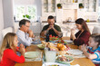 © wavebreak3 - Caucasian grandfather and parents with son and daughter sitting at table and praying before dinner