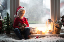 Beautiful Toddler Child, Boy, Waiting On The Window On Christmas Eve, Looking For Santa Claus