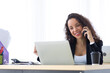 © NVB Stocker - Hispanic business woman talking on mobile phone busy working laptop computer at office. Drink coffee