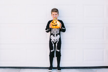 Boy In Halloween Costume With Pumpkin