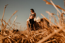 Young Pregnant Woman In A Wheat Field. Concept Pregnancy Session