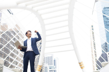 Celebrating success arms raised. Cheerful Asian business man celebrating success outdoors